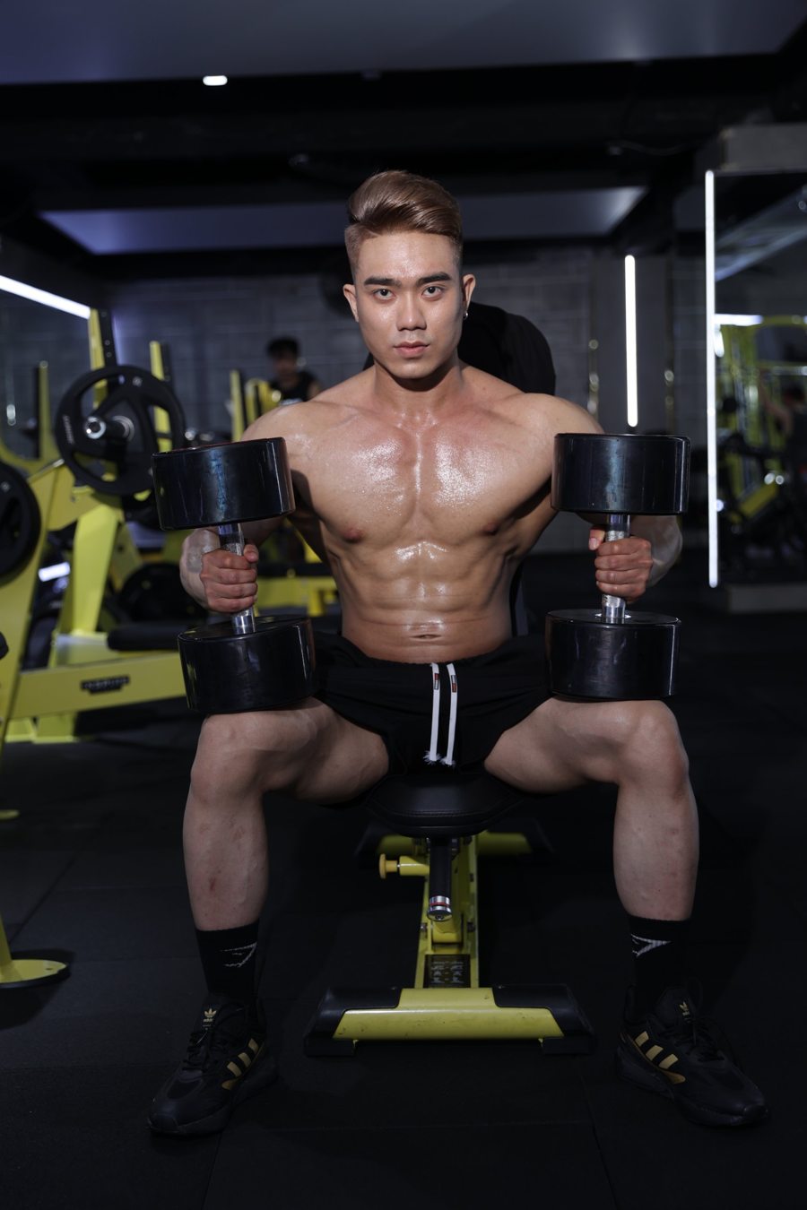 Jeff seated on a bench with heavy dumbbells before a press